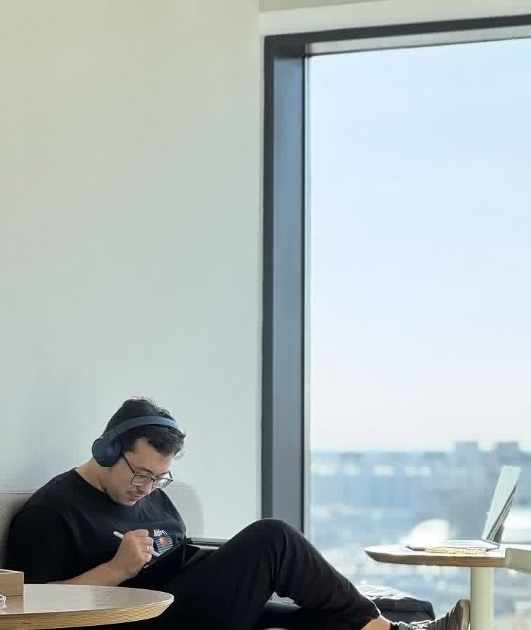 Bekzat sketching on a tablet by a window
